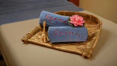 A massage table with folded towels and a small basket in a dimly lit room.