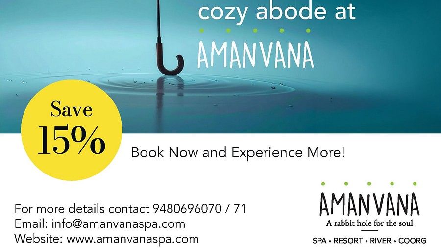 Orange umbrella in rain with water droplets against blue sky, advertising Amanvana Spa Resort, Coorgs monsoon experience with 15% discount offer