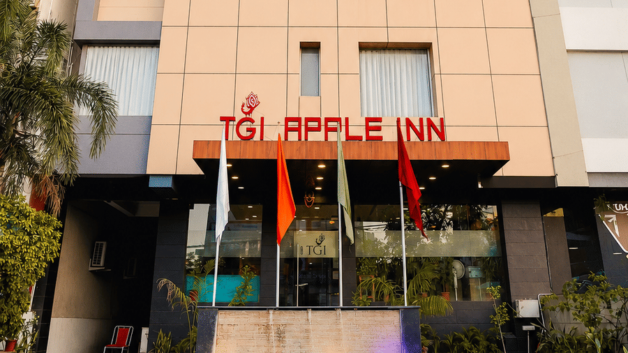  Exterior view of the multi-story Apple Inn hotel building featuring modern paneling, red entrance signage, and flags near the front entry - TGI Apple Inn, Ajmer
