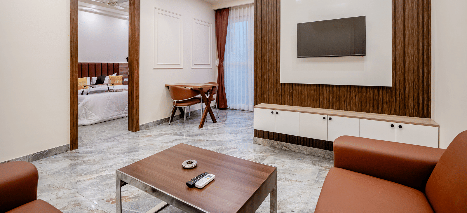 Spacious living area with sofa set, table, and wall-mounted TV at Lime Tree 1BHK Service Apartment Near Artemis Hospital Gurgaon.