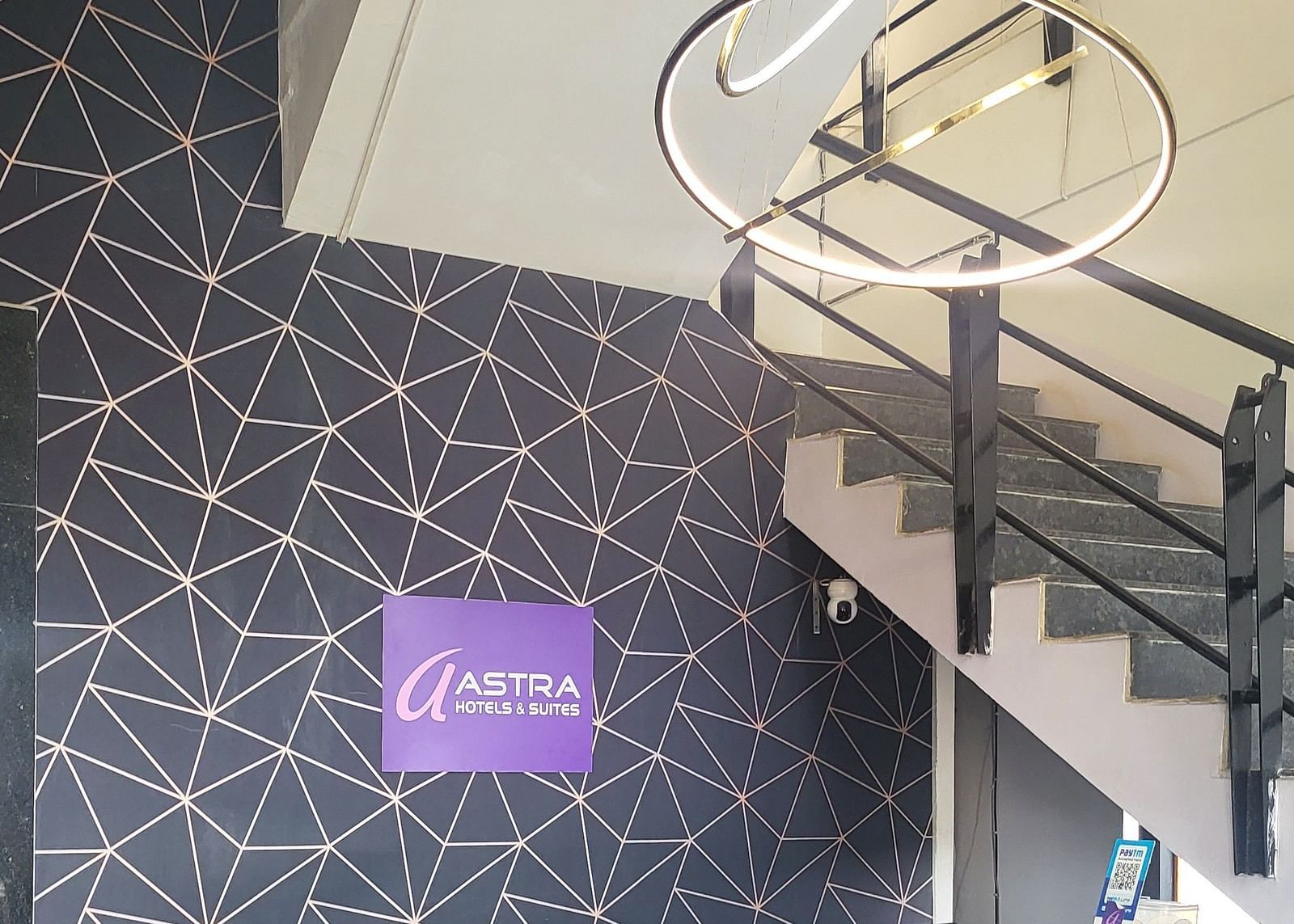 A stylish hotel staircase with a spiral metal railing, decorative wall lighting, and a modern interior design - Astra Hotels & Suites, Sarjapura