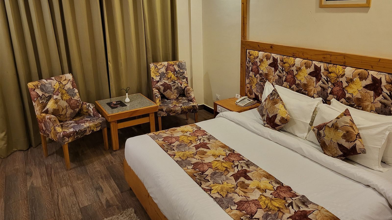 Side angle of the bedroom, featuring comfortable seating, elegant curtains, and wooden flooring at Dagshai Manor Kasauli - Inde Hotels.
