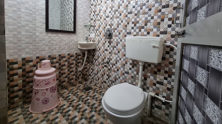 A bathroom with a medium sized half mirror along with a commode and a shower area at the Dream Vision Guest House.