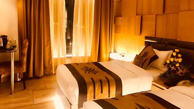 A Superior Twin Bed Room at JRD Pride - Business Hotel featuring twin beds, an accent wall, wooden flooring, and warm lighting.