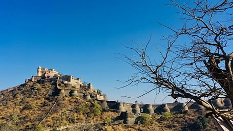 An overview of Kumbhalgarh Fort with stone structure on a hilltop under a clear blue sky.