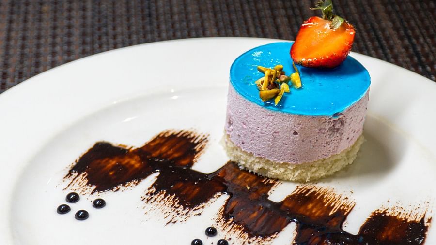 A plate with a small, decorated cake and dark garnishes.