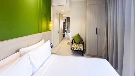 A hotel room with a large bed, a comfortable chair and a cupboard - Wonder Hills