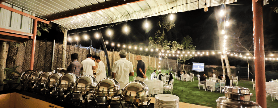 Outdoor buffet setup for a destination wedding at Ibex Resorts, Coimbatore (Kakarla), with elegant dining arrangements under ambient lighting.
