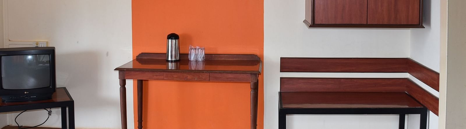 A room at Wind Chalet Resort featuring three sets of tables next to each other: one with a TV, another with essentials, and the third placed beneath a wall-mounted wooden cupboard.