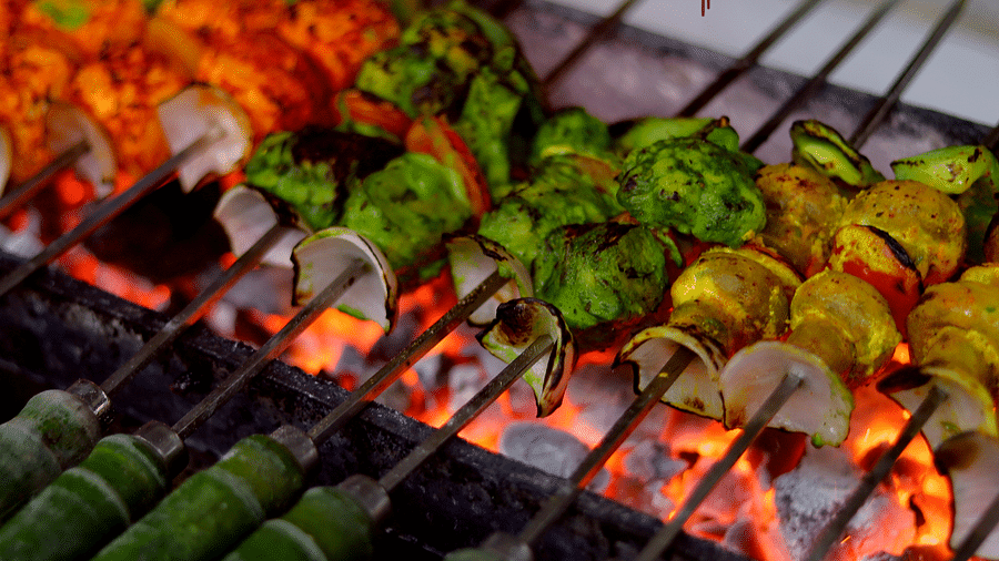 Grilled skewers of meats and vegetables over glowing coals, showcasing the grilling process - Themis Barbecue House, Ambience Mall, Gurugram