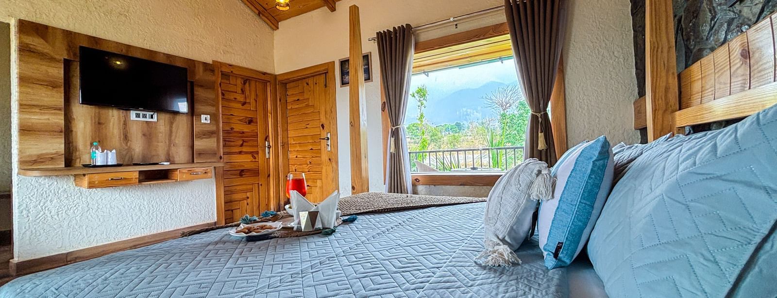 Comfortable resort room with king size bed, TV unit, and warm interiors at Corbett Nirvana Resort