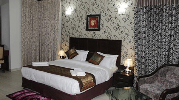 Double bed with a quilted headboard, white linen and a patterned accent wall.