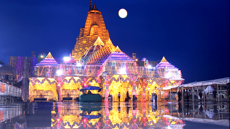 An ornate, ancient temple lit up at night with a full moon.