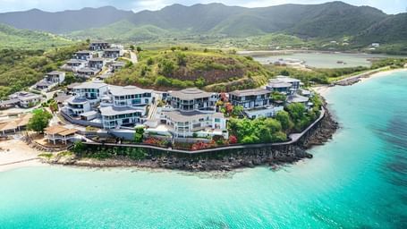Aerial view of Tamarind Hills Resort and Villas in Antigua, perched on a scenic peninsula with turquoise waters, sandy beaches, and lush green hills.