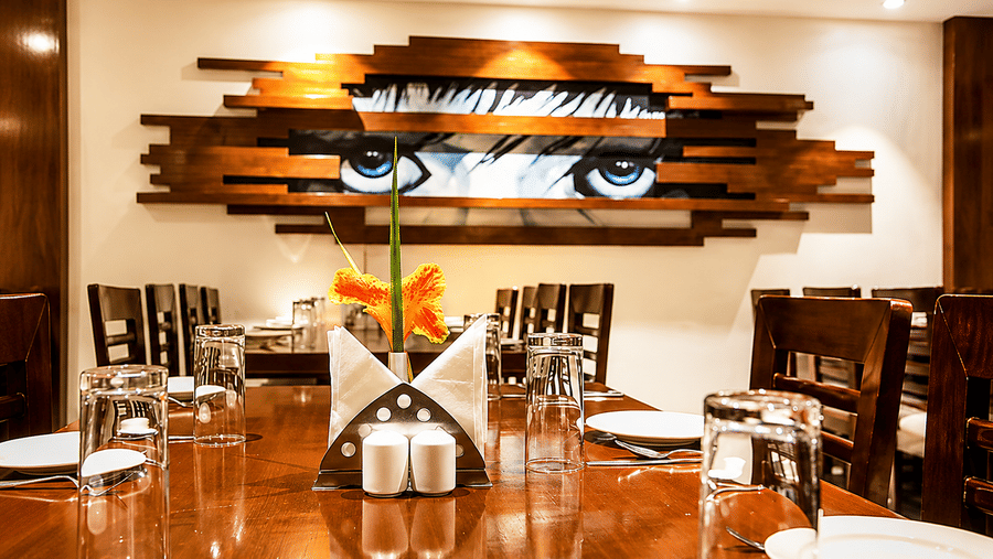 Restaurant seating with a striking eye themed wall art installation above the tables at Eastlynn Resort, Rishikesh.