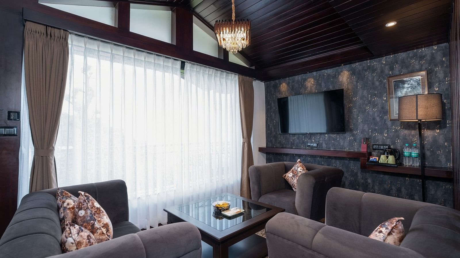 Image of a living room featuring two sofas, a television and an expansive window.