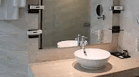 A bathroom with a washbasin, mirror, and towels hanging on the pipe beside it, creating a functional space.- Golden Suites, Gurgaon