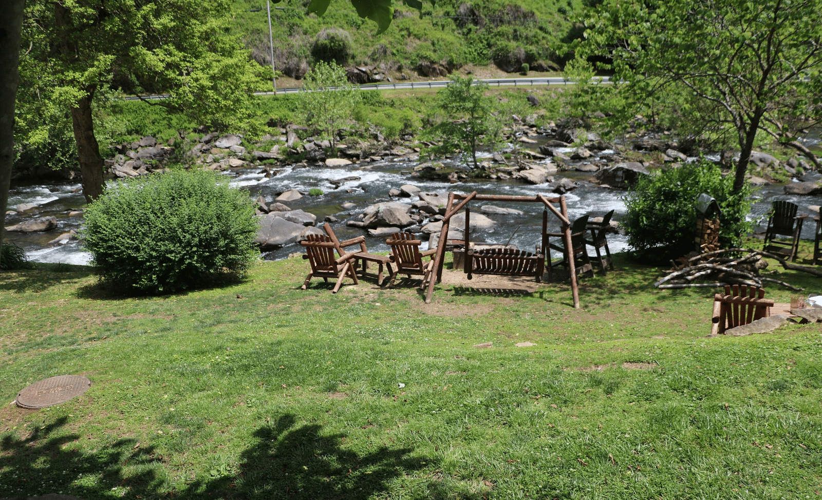 a wooden swing and two wooden arm chairs kept on the bank of a river stream - Historic Tapoco Lodge