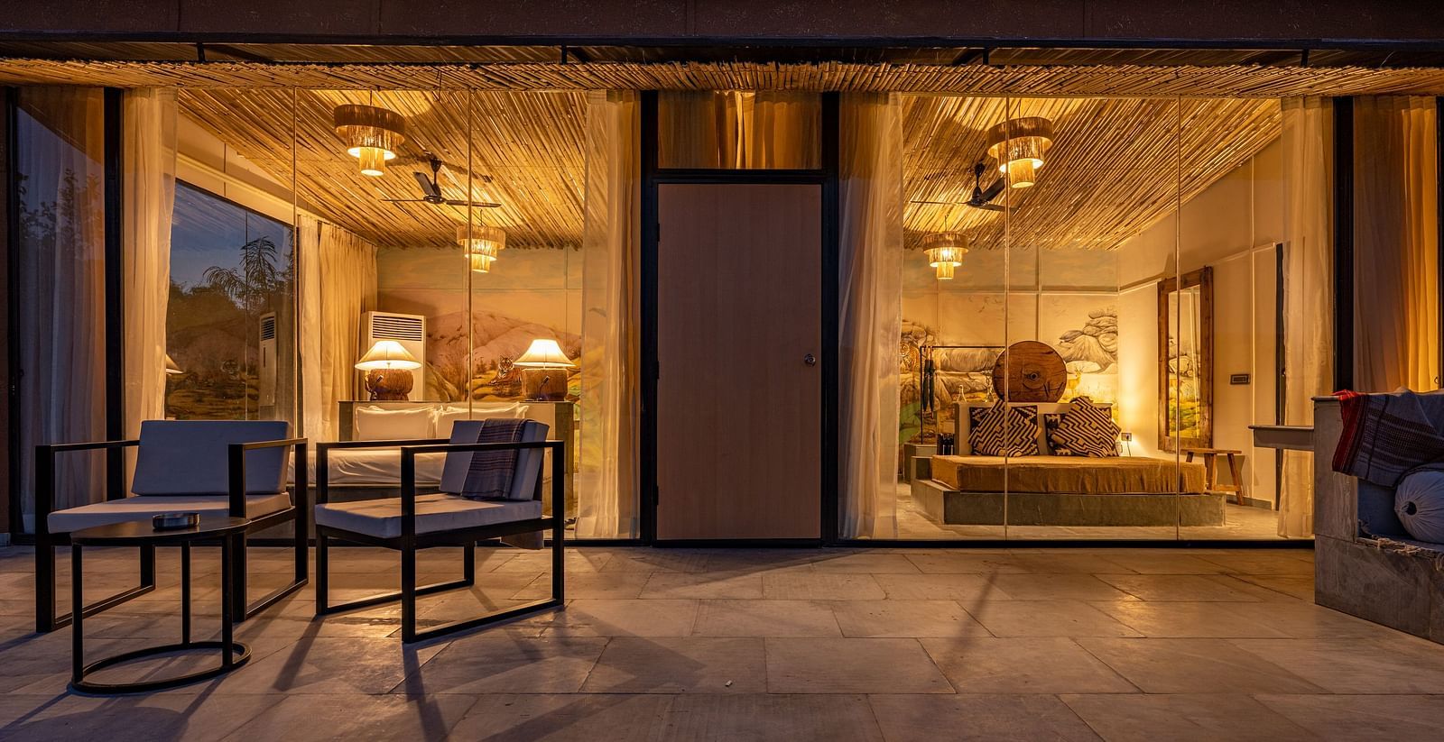 A facade image of a room with bright decorative lighting with outdoor seating arrangement - Utsav Camp Sariska