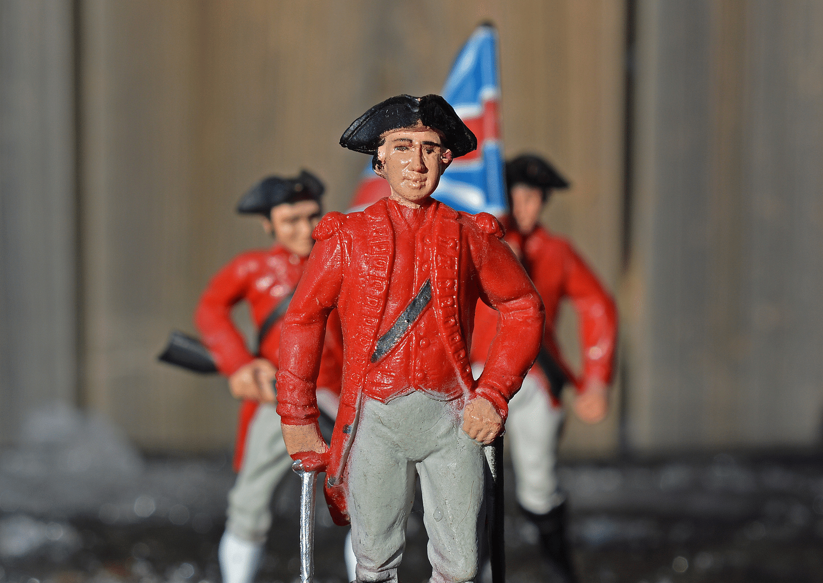 Three action figures of british soldiers shown with 1800s uniform and a flag.