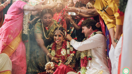A traditional Indian wedding scene with the bride and groom surrounded by vibrant colours and floral decorations.