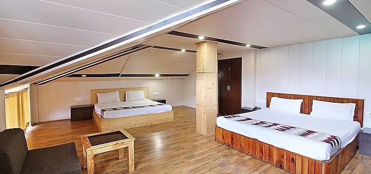A room at DLS Hotel Devlok, Manali with a sloping roof line alongside a sofa chair and a coffee table