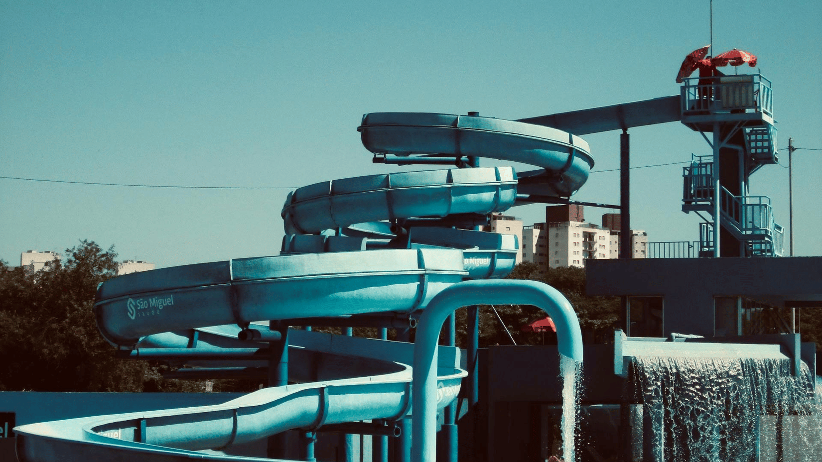 A slide ride at a water park with circular slides reaching a waterbody at the bottom