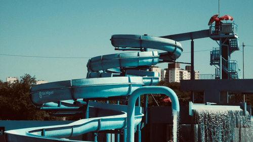 A slide ride at a water park with circular slides reaching a waterbody at the bottom