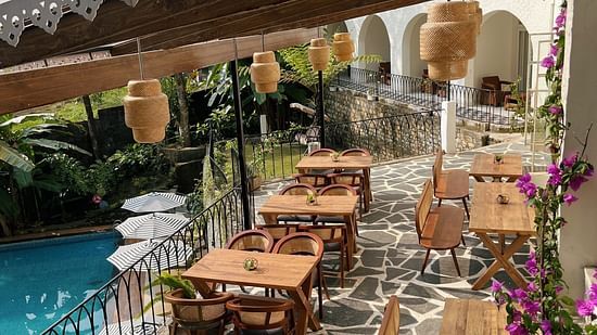 Outdoor dining patio with wooden tables, wicker chairs, and a pool view. - VITS Select Kunjham, Gangtok