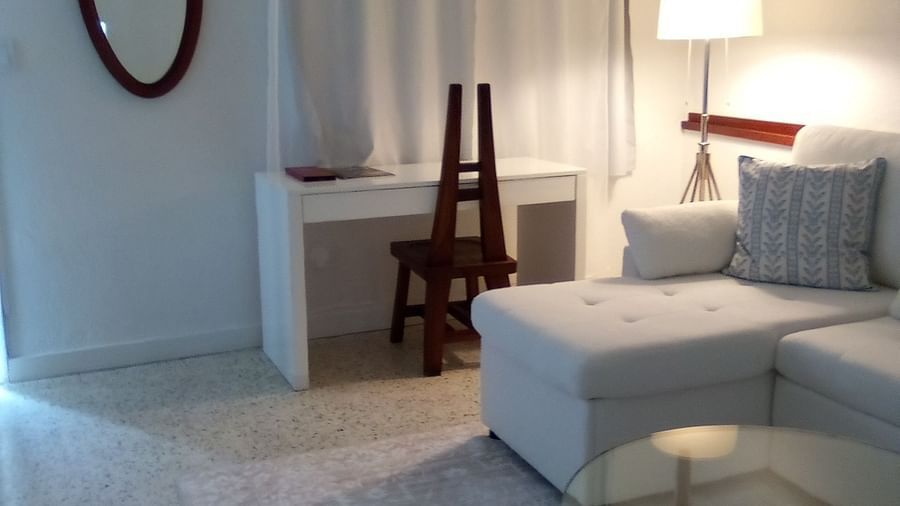 Casa Morada room with a bed, a floor lamp, an oval mirror, and a small glass coffee table.