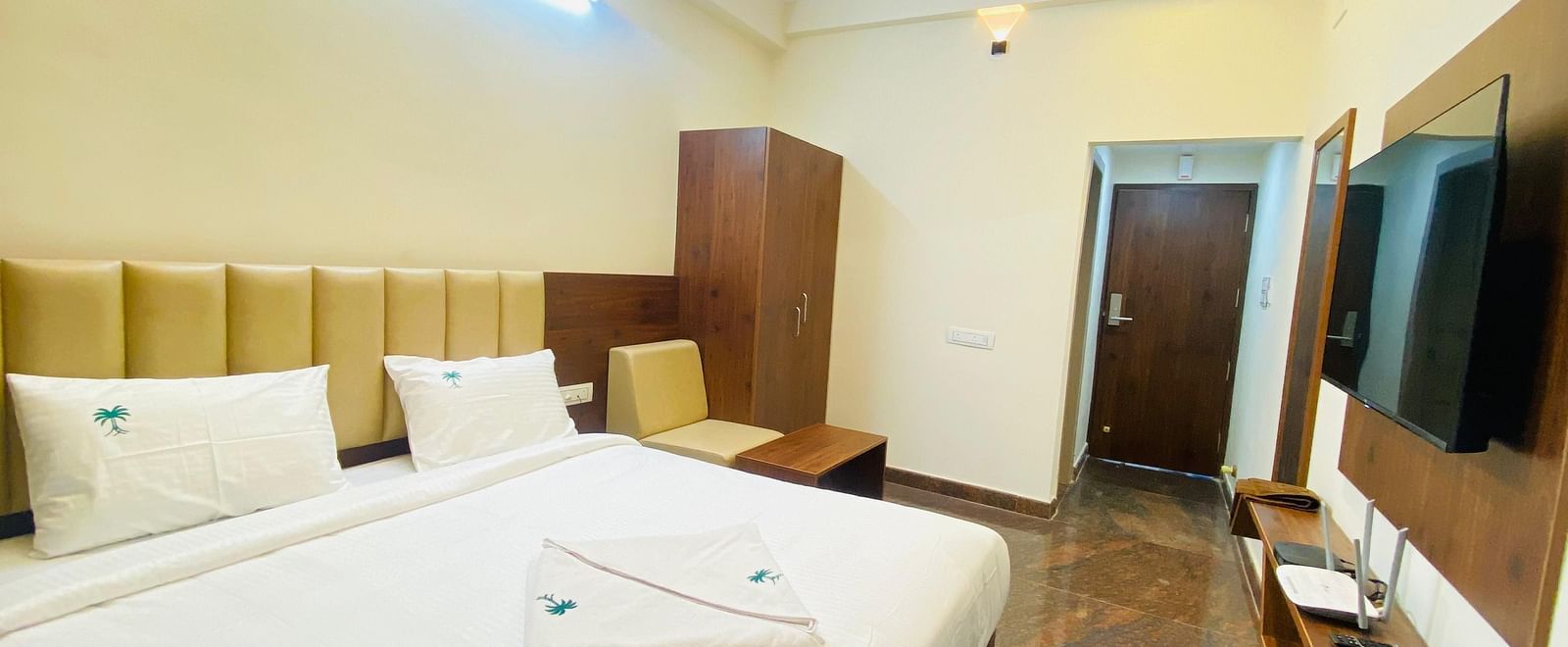 Well-lit deluxe room with plush bedding and stylish wood accents for a restful stay at Hotel Sahara Tree.