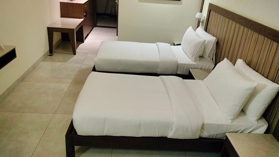 An image of a twin bed with a photo frame on the wall and a light is hanging from the ceiling - VITS Lonvala