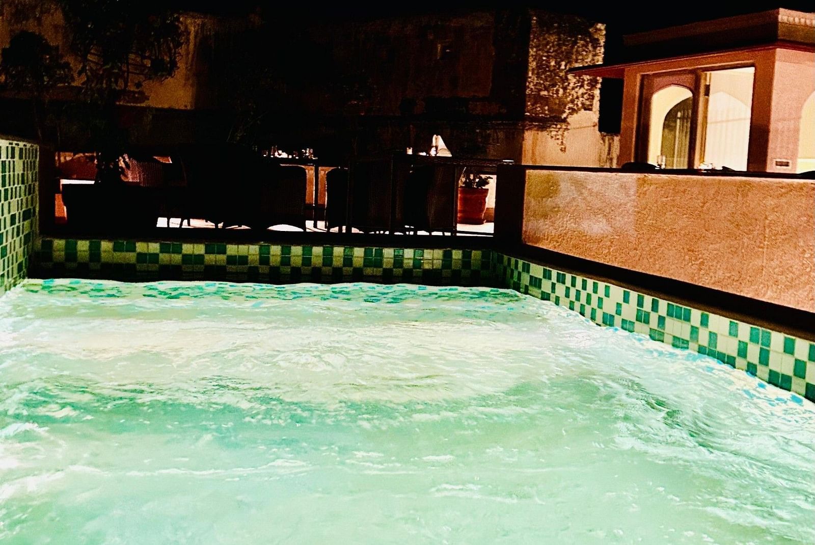 Elegant indoor swimming pool at Surya Haveli with ambient lighting and a luxurious dark-toned design.