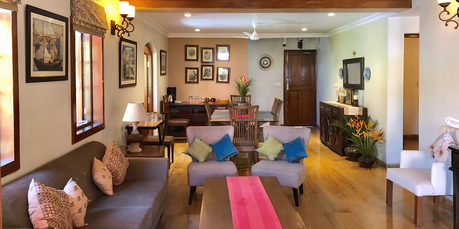 Living Area featuring a four seater sofa along with three couches behind which there is a six-seater dining table 