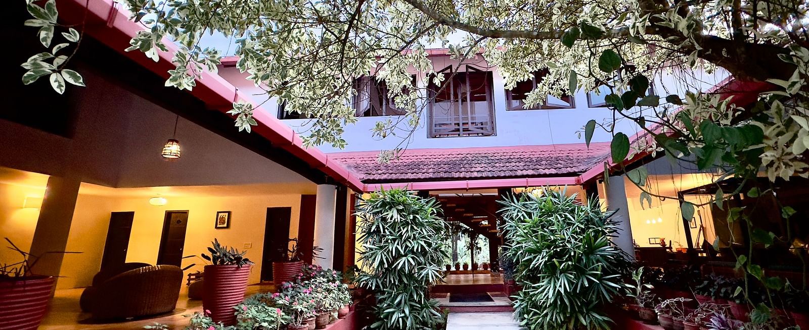 an open area in the interior of the hotel with bushes and flower pots - Kadkani River Resort, Coorg