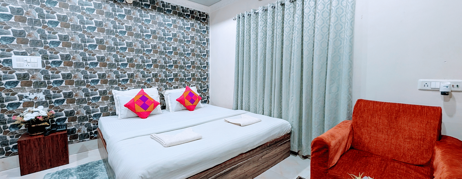 image of the standard room at dip holidays featuring a double bed and orange coloured cushioned couch