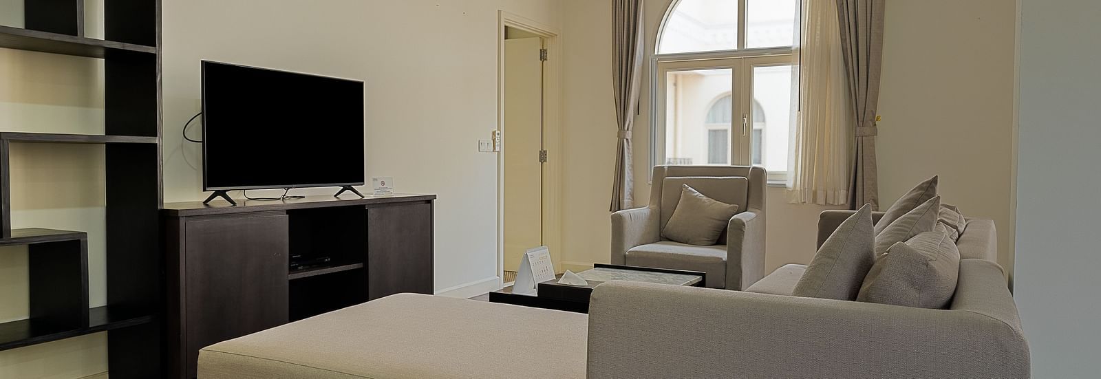A living room with a white sofa, a TV, and a large window | Four-bedroom Suite | Central Mansions, Phnom Penh