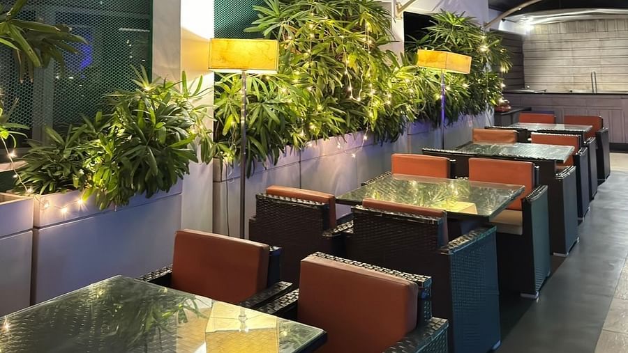 Dining area with tables, chairs, and potted plants at the side of Cenneys Gateway.