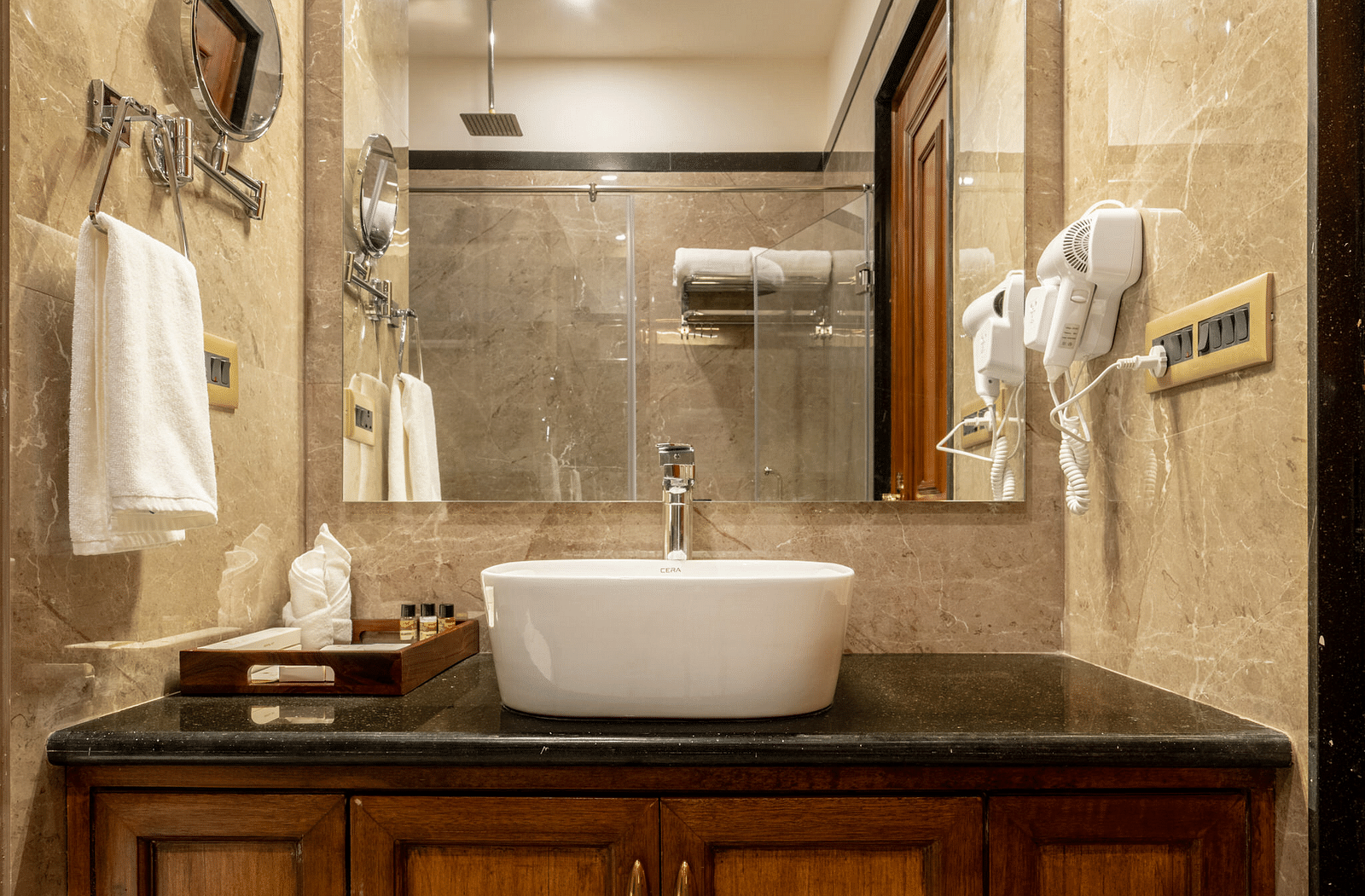 a wash basin with a covered vanity area along with a huge square shaped mirror - Brij Castle, Jaipur