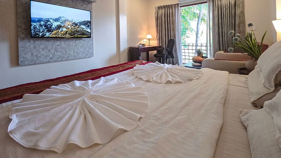 A spacious bedroom with a bed, towel art, and a wall-mounted flat-screen TV – The Verda de Miranda Resort.