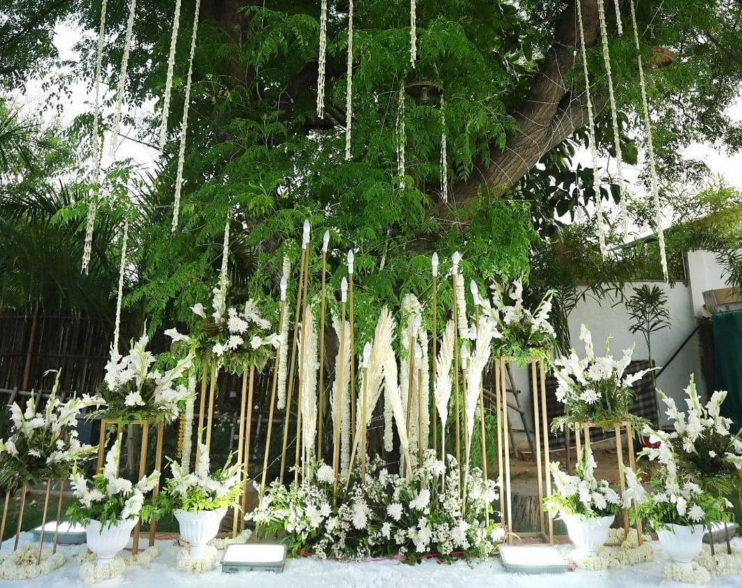Hanging white flowers and vertical bamboo arrangements forming a decorative aisle at Tisya Farms, Gurgaon.