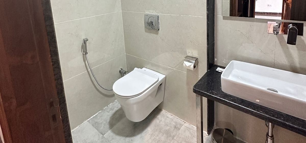 A compact bathroom includes a white toilet and washbasin with a mirror - Kankidham Lords Inn