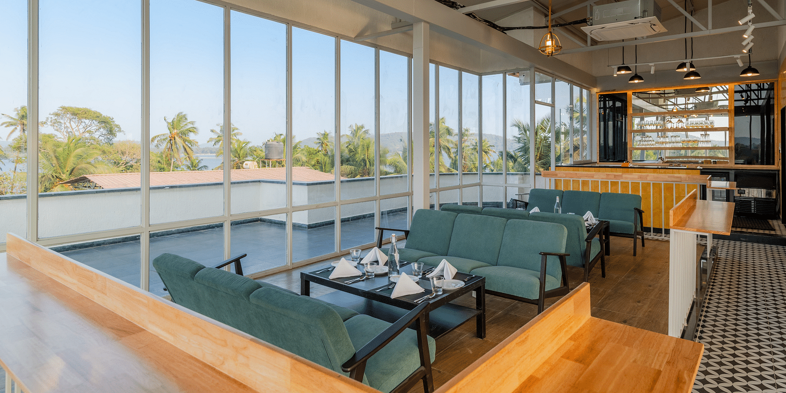 Spacious cafe interior with large windows and comfortable seating at Bedzzz Xclusiv Morjim, Goa