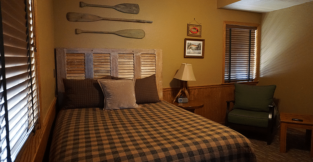 A room with a double bed and wooden oars hung on the wall behind it at Shaver Lake Village Hotel.