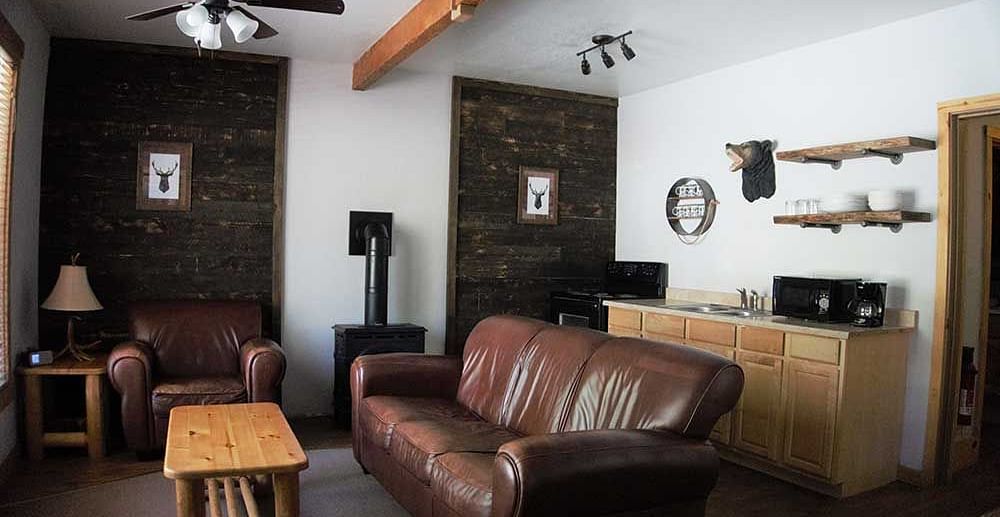 A room at Shaver Lake Village Hotel with a double sofa placed in its center and a wooden coffee table placed in front of it.