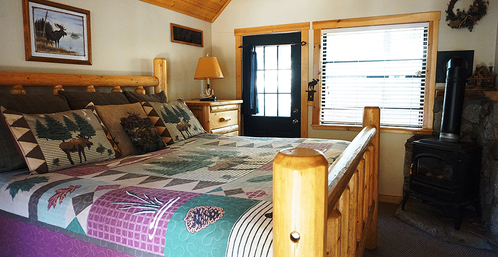 A room with a double bed and wooden paneling on the ceiling at Shaver Lake Village Hotel.