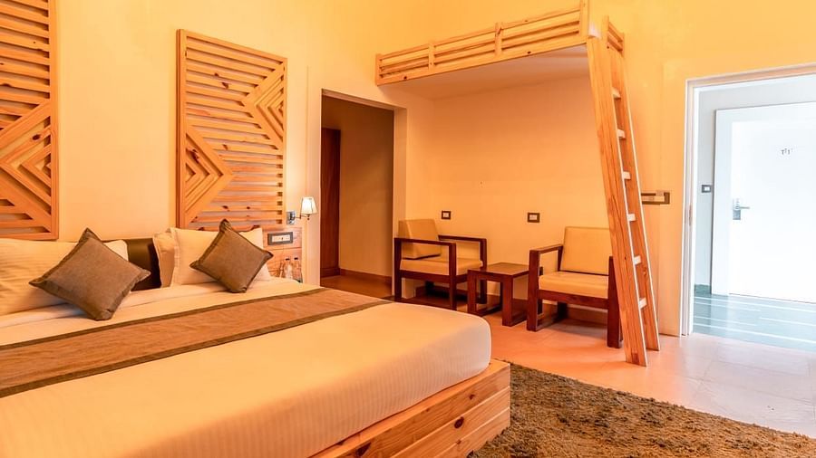 A bedroom with a bed, warm lighting, interior setting, with a doorway leading to another room - Clarks Exotica Resort, Near Mukhteshwar.