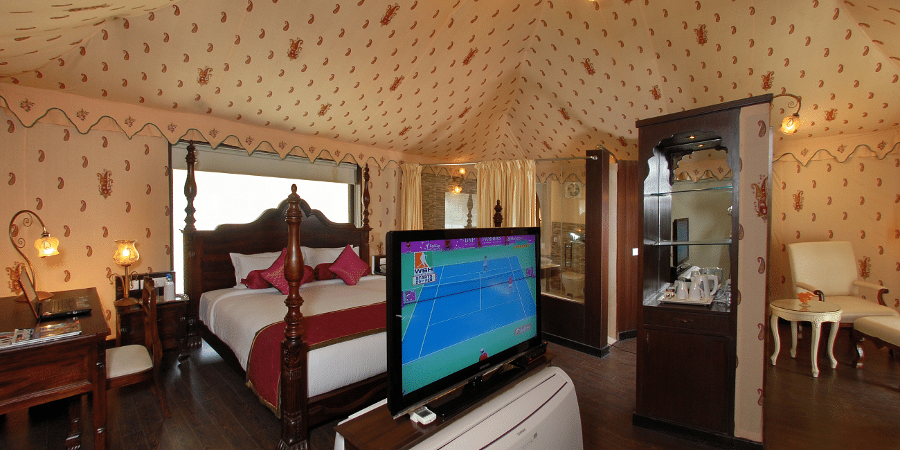 Image of room with a bed and a television in front of the bed at Rajasthali Resort & Spa Jaipur.