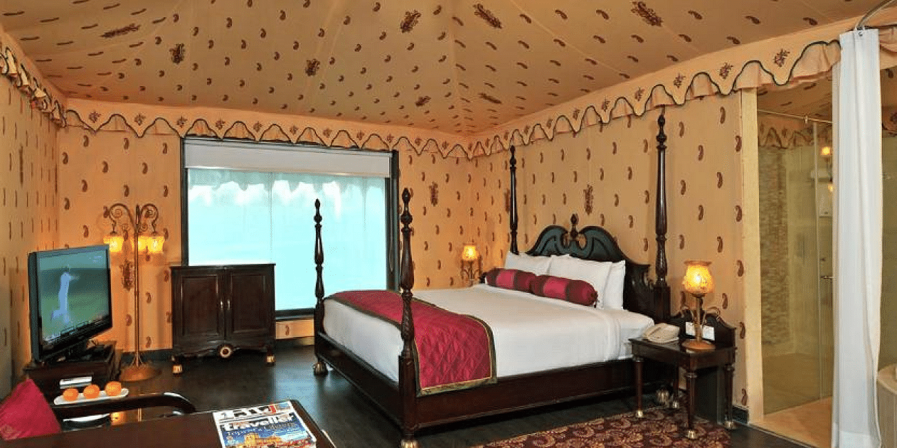 Side view of a room with a bed and a television in front of the bed at Rajasthali Resort & Spa Jaipur.