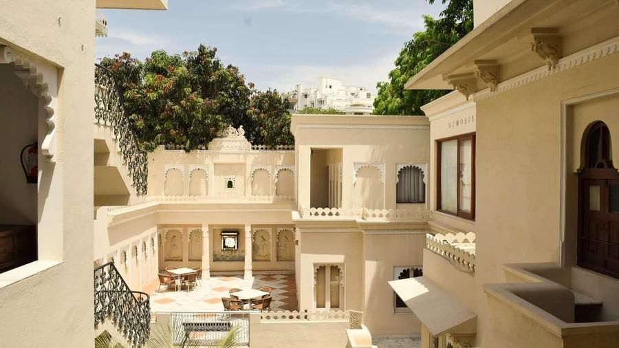 Courtyard with Rajasthani architecture, carved arches, staircase, and outdoor seating area at Ram Pratap Palace, Udaipur.